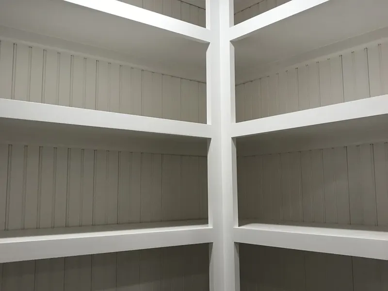 White painted built-in corner shelving with beadboard backs and crown molding