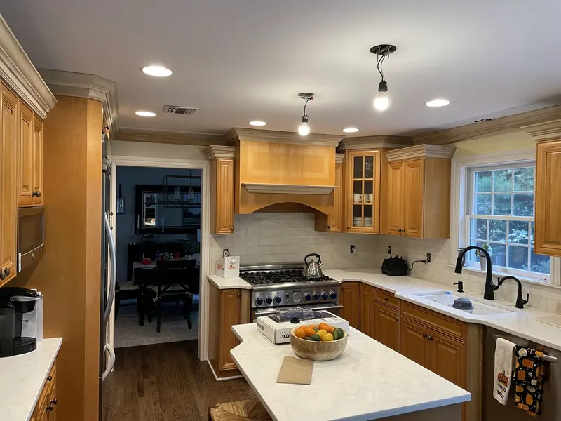 Finished kitchen with maple cabinetry, a wood range hood, and a white quartz island