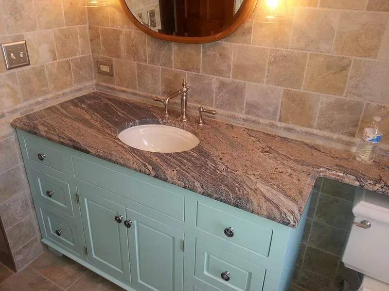 Bathroom vanity with a granite top, undermount sink, and tiled walls