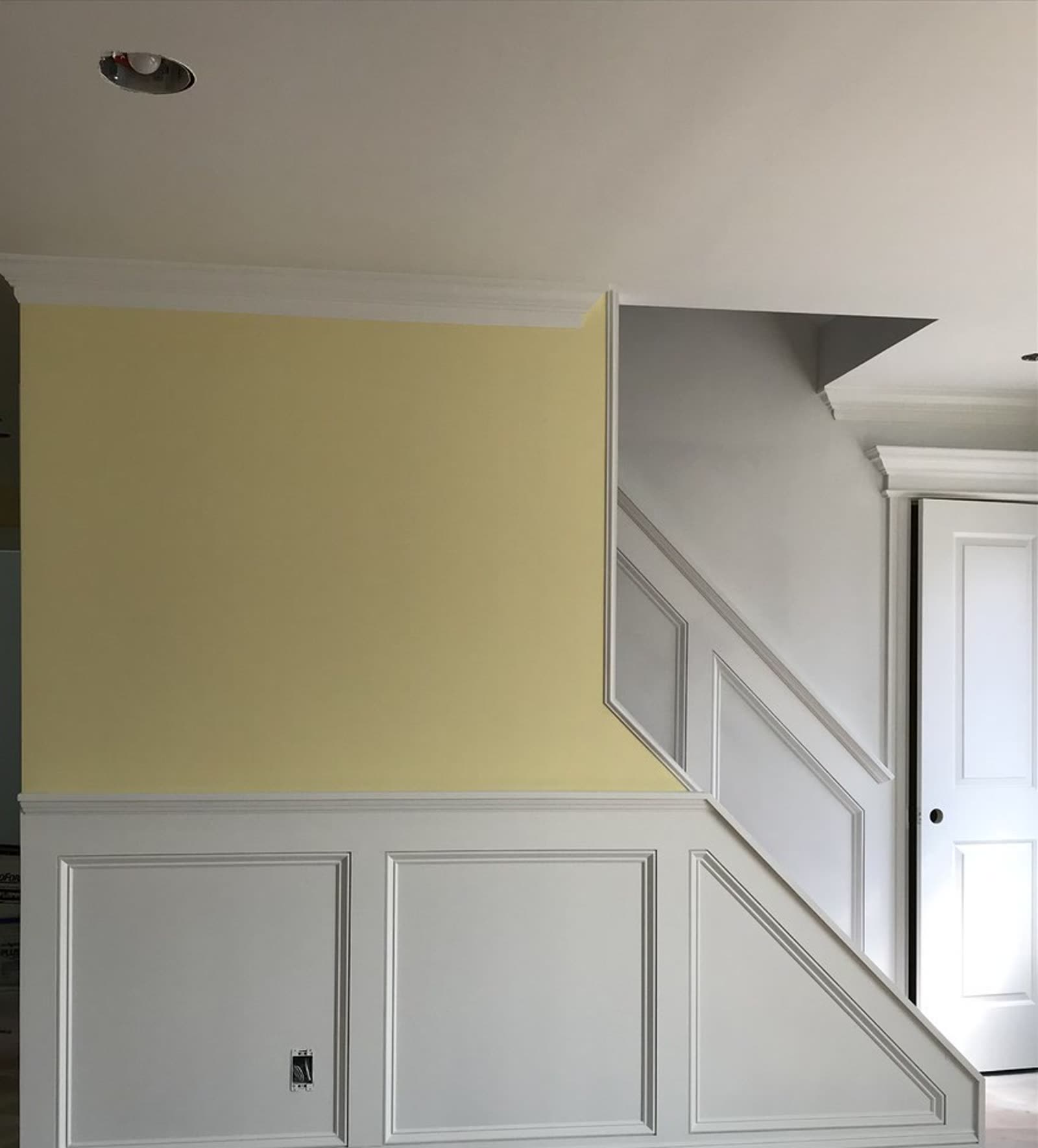 Finished custom millwork: raised-panel wainscoting, crown molding, and staircase trim built by Old Town Renovations in a Long Island home